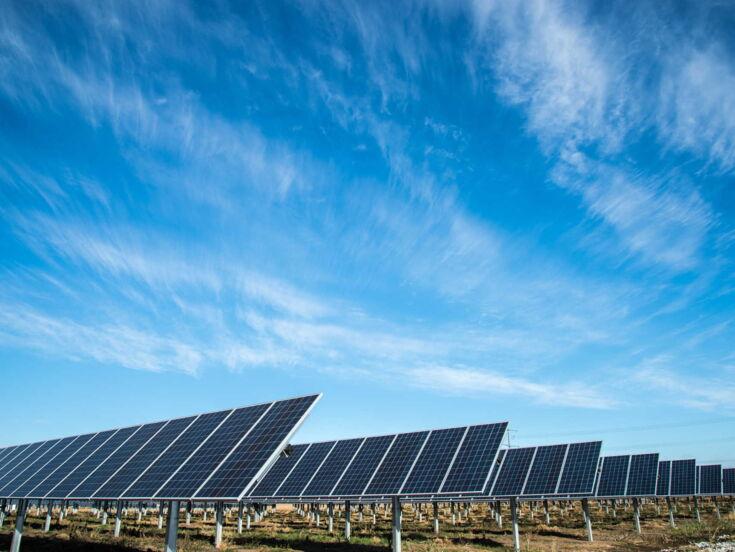 Viele Solaranlagen auf einem Feld bei Sonnenschein und blauem Himmel