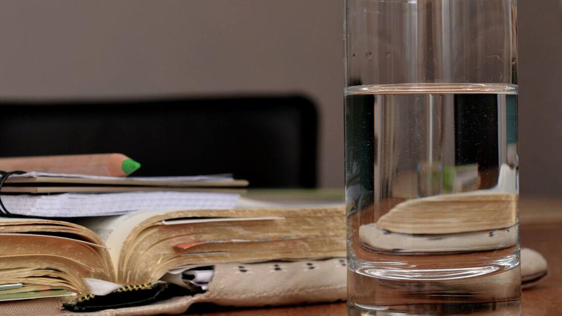 Ein Buch und ein Glas Wasser auf einem Tisch