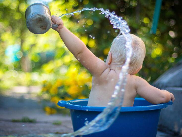 Baby spielt mit Wasser in Wanne