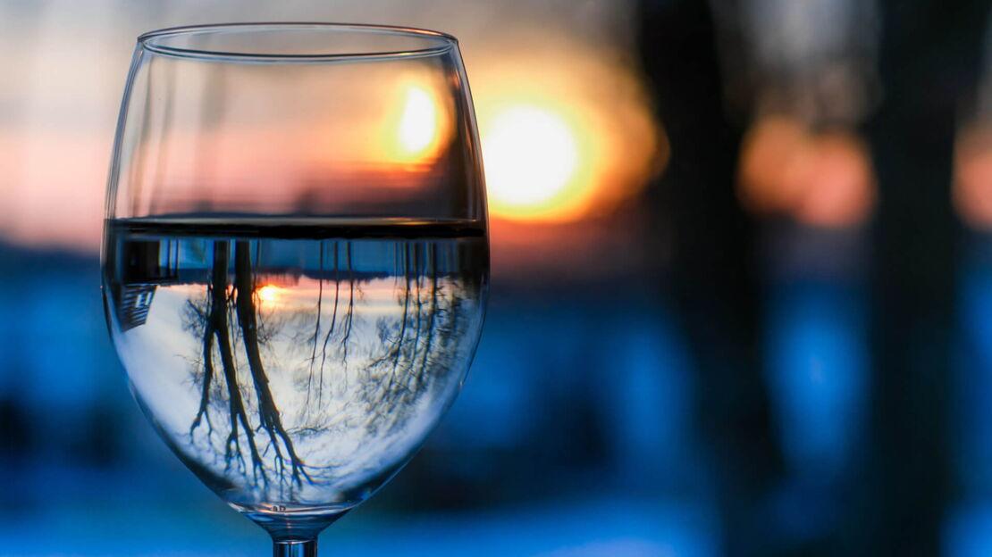 Winterlandschaft spiegelt sich in einem Weinglas mit Wasser