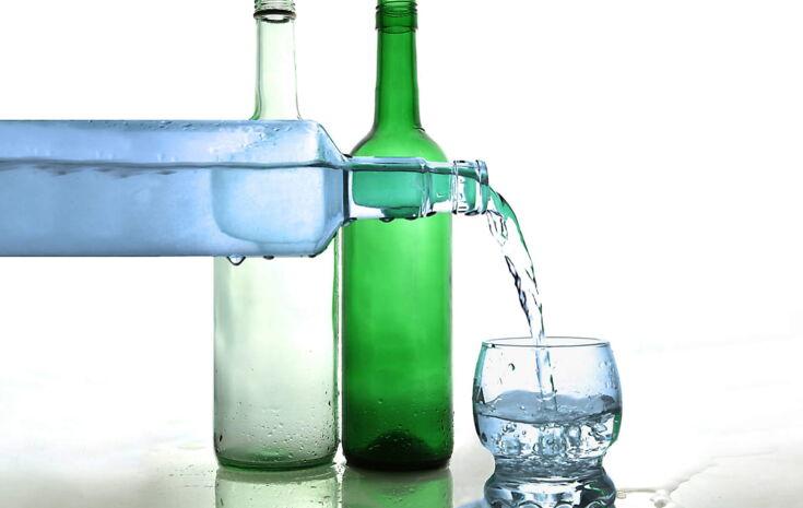 Verschiedene Wasserflaschen und ein Wasserglas