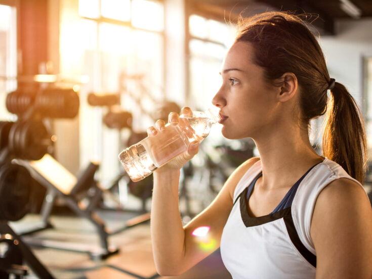 Sportliche junge Frau trinkt Wasser in einem Fittnesstudio