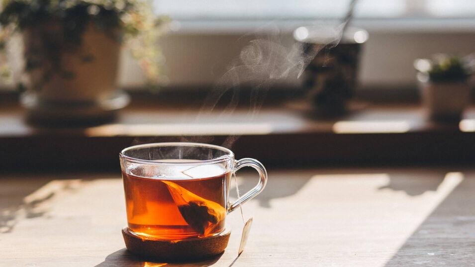 Bronzefarbener Tee in Glastasse im Sonnenschein