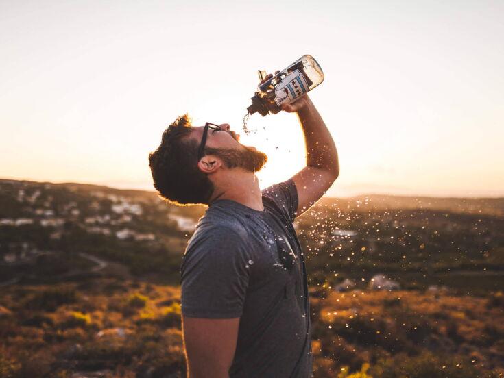 Mann trinkt Wasser aus Flasche in Natur