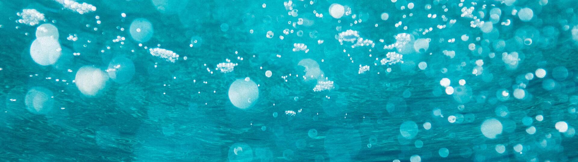 Unterwasserfotografie von Wasserblasen die in der der Sonne glitzern.