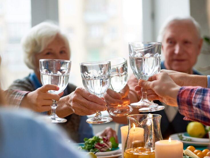 Eine Familie sitzt am Tisch und stößt mit Wasser an