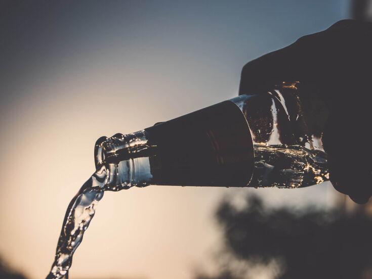 Ausgießen einer Glasflasche im Sonnenuntergang