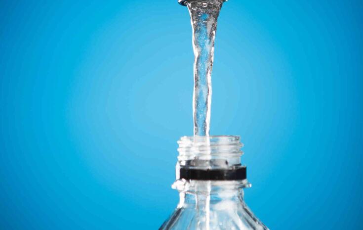 Leitungswasser fliesst aus Wasserhahn in Plastikflasche