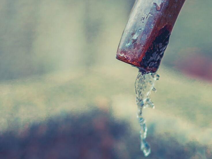 Wasser tropft aus einem Hahn in einen Brunnen