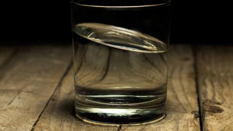 Wasserglas auf einem Holztisch mit schrägem Wasserstand