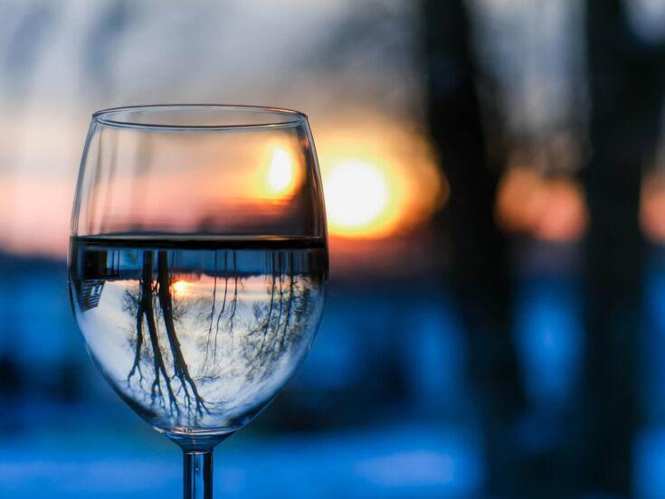 Winterlandschaft spiegelt sich in einem Weinglas mit Wasser