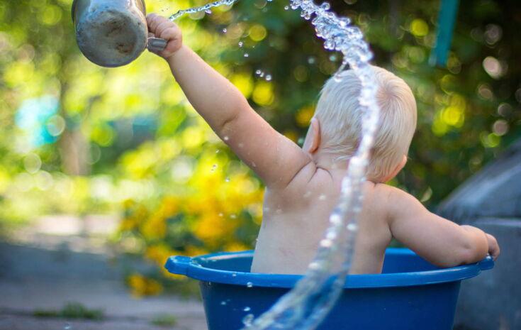 Baby spielt mit Wasser in Wanne