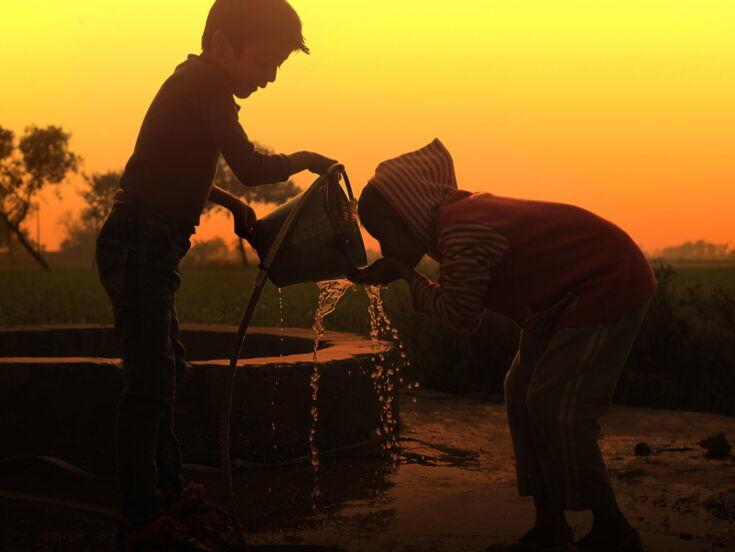 Kinder trinken Wasser aus Brunnen