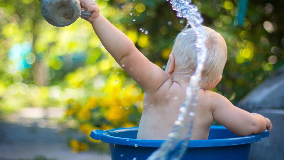 Baby spielt mit Wasser in Wanne