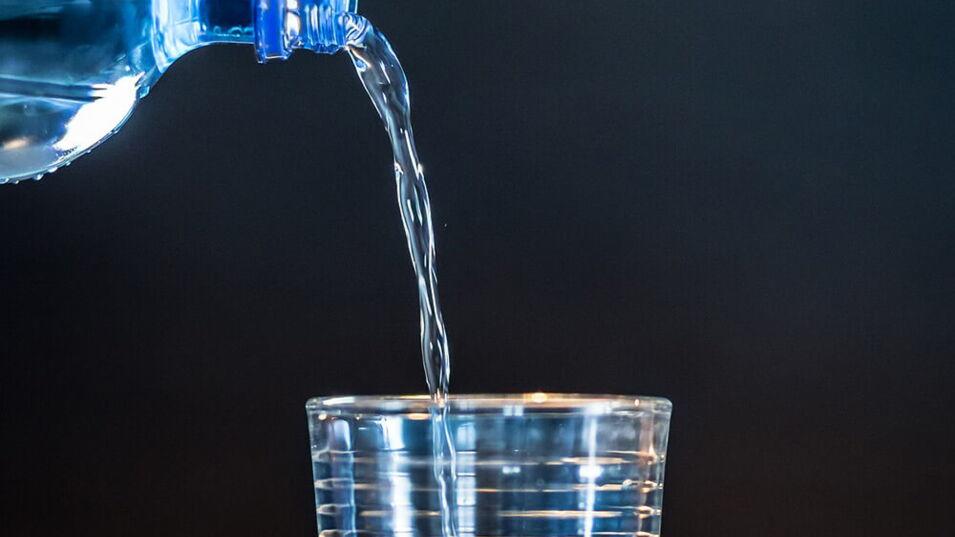 Mineralwasser aus einer Flasche wird in ein Glas gegossen