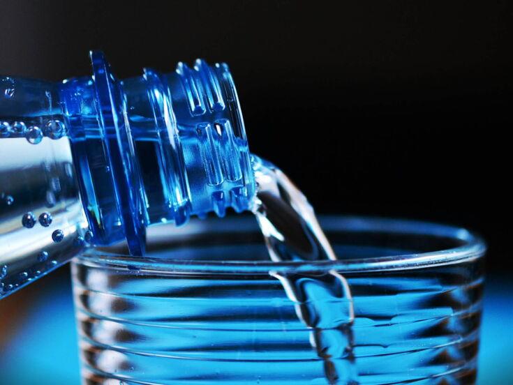 Wasser aus Plastikflasche in Glas eingießen