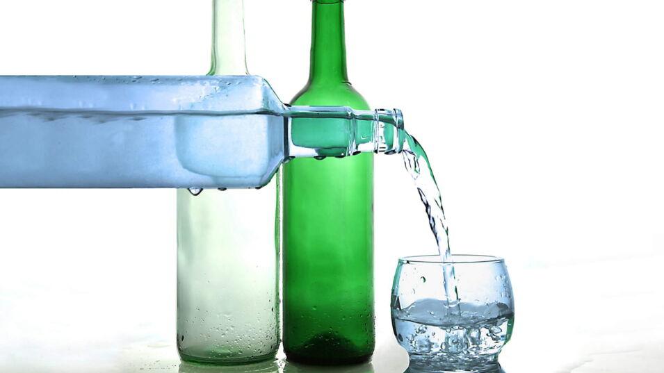 Verschiedene Wasserflaschen und ein Wasserglas